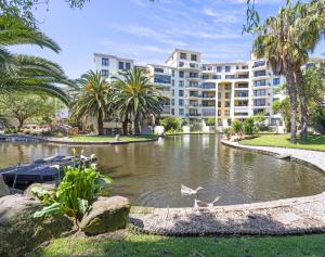 a hotel with a pond in front of a building at Capri On Lake in Cape Town