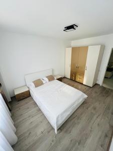 a bedroom with a large white bed and wooden floors at SNC Residence V in Şelimbăr