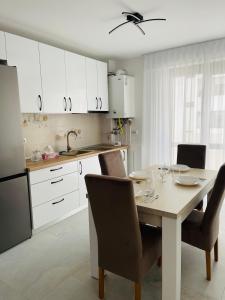 a kitchen with a table with chairs and white cabinets at SNC Residence V in Şelimbăr