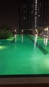 a large swimming pool with green water at night at Sensorizza @ Sensory Residence in Kampong Tangkas