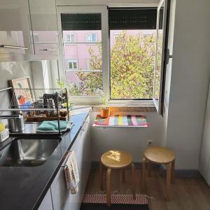 uma cozinha com 2 bancos, um lavatório e uma janela em Casa do João • City Break • Lisbon em Lisboa