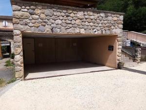 un garage avec un mur en pierre et deux portes de garage dans l'établissement Studio meublé indépendant tout confort classé 2**, à Aubenas 2 autres photos