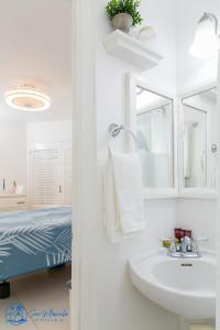 baño blanco con lavabo y cama en Sea Miracle Villa/Beach Cottage, en Silver Sands