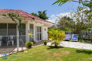 a house with a yard with chairs and a fence at Sea Miracle Villa/Beach Cottage in Silver Sands