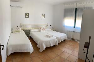 two beds in a room with white walls and tile floors at FINCA VALDELAJARA a 20 minutos de Puy du Fou in Toledo