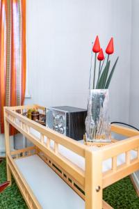 una mesa con radio y un jarrón con flores rojas en Grandma Tyyne's home, en Rovaniemi