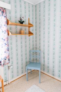 a blue chair sitting in a room with wallpaper at Grandma Tyyne's home in Rovaniemi