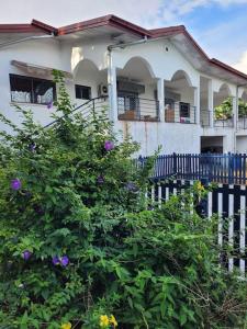 een wit huis met een hek en bloemen ervoor bij Villa bleue in Kribi