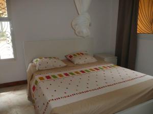 een witte slaapkamer met een bed met kussens bij Villa bleue in Kribi