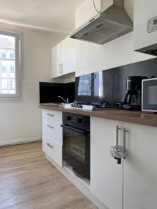 uma cozinha com armários brancos e um forno com placa de fogão em Spacieux - lumineux - 3 couchages - Quimper centre em Quimper