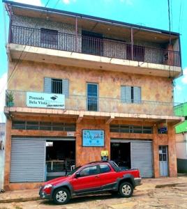 un coche rojo estacionado frente a un edificio en Pousada Bela Vista, en São Thomé das Letras