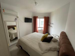 ein Schlafzimmer mit einem Bett und einem großen Spiegel in der Unterkunft Itapema-Meia Praia- 3 quartos - Frente Mar! in Itapema