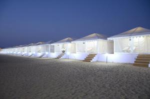 a row of white tents on the beach at night at Ozaki Desert Camp & Resort in Jaisalmer
