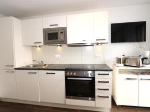 a white kitchen with a stove and a microwave at Kometer App Enzian in Fendels