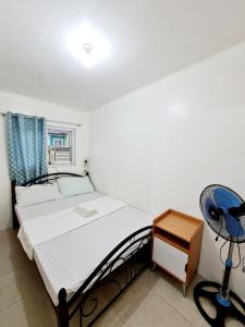 een slaapkamer met een bed, een ventilator en een bureau bij Calapan City Cheapest House Transient Guest Rental L39 in Calapan