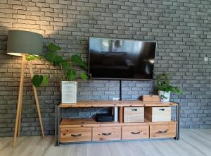 Apartment Rybaki في غدانسك: غرفة معيشة مع تلفزيون على جدار من الطوب