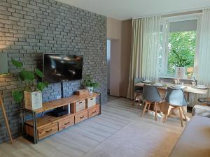 Apartment Rybaki في غدانسك: غرفة معيشة مع تلفزيون بشاشة مسطحة على جدار من الطوب