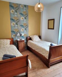 Un dormitorio con dos camas y una pared con flores. en Gîte Homard - Bord de mer - 4/6 personnes, en Quinéville