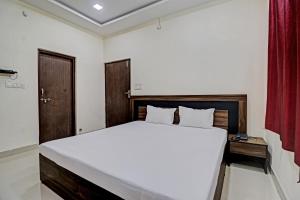 een slaapkamer met een groot wit bed en een rood gordijn bij Hotel Midway Treat Dhar in Dhār