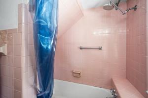 een roze badkamer met een douche met een blauw douchegordijn bij Julia Place in Sarasota