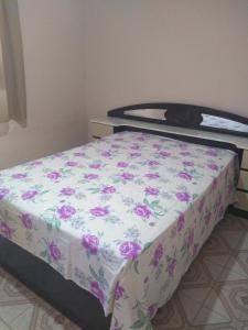 um quarto com uma cama com flores roxas em Casa Santa Ana, Bananeiras PB em Bananeiras
