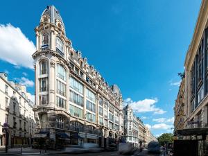 a large white building with a clock tower on a street at LivinParis - Luxury AC 2 & 3 Bedrooms Le Louvre in Paris