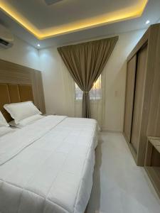 a bedroom with a large white bed and a window at شقق الايام المضيئة المخدومة in Najran