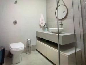 a bathroom with a toilet and a sink and a mirror at Melhor Apto no Coração de BH com Garagem e Wi FI in Belo Horizonte