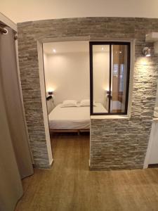 een slaapkamer met een bakstenen muur en een bed met een spiegel bij 11 rue Vauban in Antibes