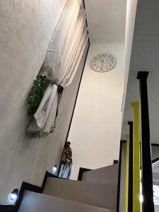 osoba stojąca na schodach z zegarem na ścianie w obiekcie Hortensja Check-in 24H w mieście Oborniki