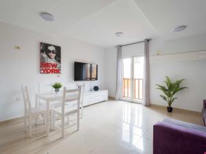 sala de estar blanca con mesa y TV en Mahostly Sun and Spa en Puerto del Rosario