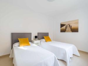 Mahostly Sun and Spa في بويرتو ديل روزاريو: سريرين مع وسائد بيضاء وصفراء في الغرفة