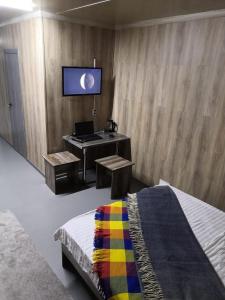 a bedroom with a desk with a laptop and a tv at The Mini-hotel on Mukanova St in Almaty