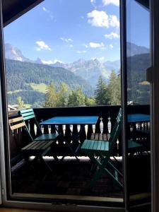 d'un balcon avec deux tables de pique-nique et une vue sur les montagnes. dans l'établissement Charmant studio idéalement situé, à Gryon