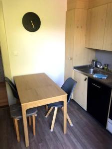 uma mesa de madeira e cadeiras numa pequena cozinha em Charmant studio idéalement situé em Gryon