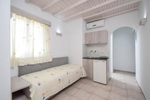 a room with a bed and a kitchen with a window at Pension Elena in Agia Anna Naxos