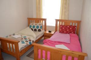 two twin beds in a room with a window at Kirk View holiday apartment in Kirkcaldy