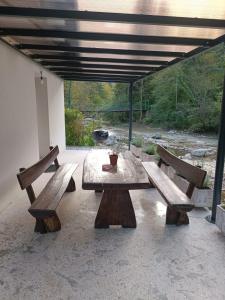 a picnic table with two benches on a patio at Riverside Guesthouse in Ig