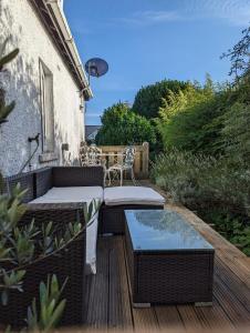 a patio with wicker chairs and a table on a deck at Cartref, 1860s family home. in Bridgend