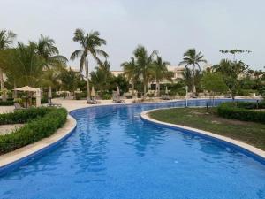 a large blue swimming pool in a resort with palm trees at Casa Salalah, cozy 2-storey townhouse in Hawana Salalah with free Wi-Fi in Salalah