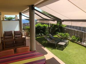 a patio with chairs and an umbrella and grass at La Tarongina apartament amb piscina in Llança