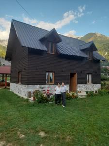 dos personas parados frente a una casa negra en Te Sofra, en Shkodër