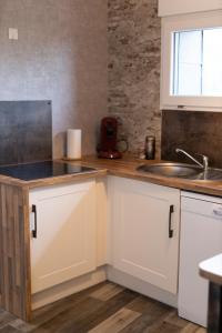 a kitchen with white cabinets and a sink at Le gîte suspendu et sa chambre cachée in Saint-Blimont
