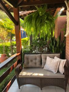 um sofá de vime sentado num alpendre com plantas em Chalé Refidim em Gravatá