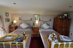 1 dormitorio con 2 camas individuales y mesa en Melorne Farm Guest House, en Camelford