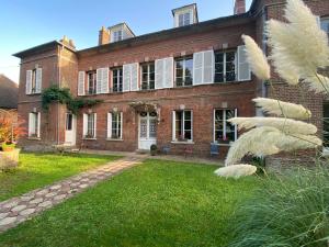 uma grande casa de tijolos com um jardim de relva em frente em MAISON 54 em Bernay