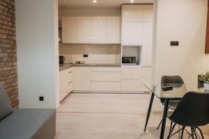 a kitchen with white cabinets and a table and chairs at Niron Apartament Kapucyńska in Piła +17 photos