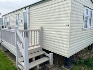 a white mobile home with a porch and stairs at Golden Sands 6 Berth Beach front Ingoldmells in Ingoldmells