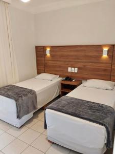 Andradina的住宿－Hotel Roda D'Agua，酒店客房设有两张床和木制床头板。