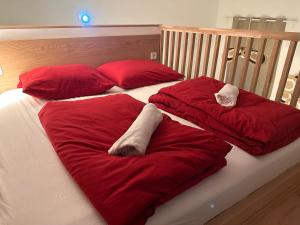 a bed with red blankets and pillows on it at Loft Apartment am Brunnenmarkt in Vienna